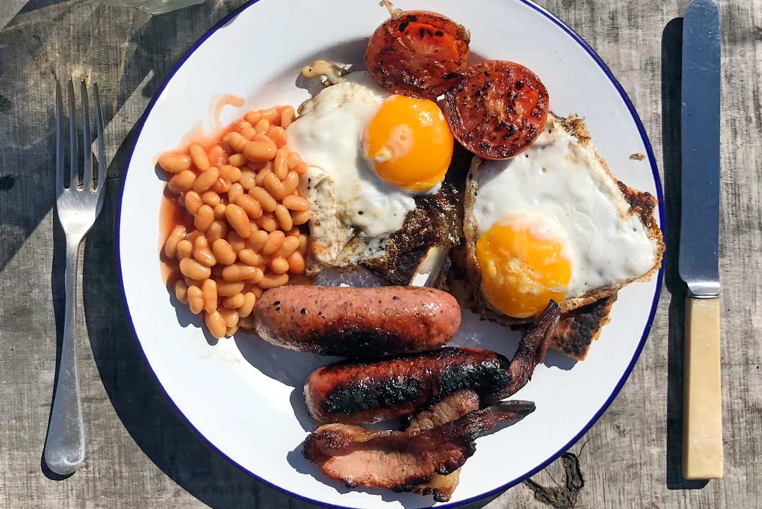 Breakfast cooked on the campfire ready to eat outside on an enamel plate with retro cutlery. Find out more guest information about Glamping at Wallops Wood and our booking extras