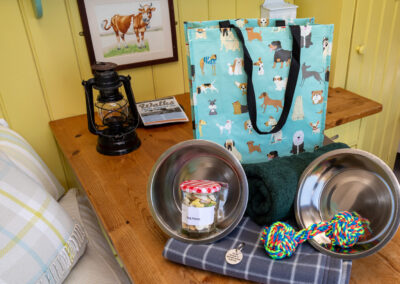Doggy Hamper on the table of Boundary shepherd's hut and it includes towel, throw, eating bowls, treats, new toy and engraved collar tag with our contact details
