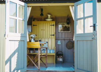 Open double doors to the living space in Barrow shepherd's hut, decorated in retro yellow and pale grey tones
