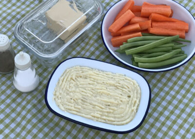 Fish pie, carrots and green beans with salt and pepper pots on a green and white gingham table cloth, Glamping at Wallops Wood