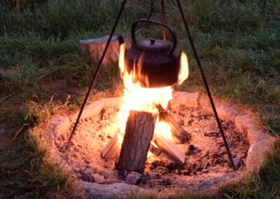 Large black kettle being licked by the flames of the campfire outside Barrow shepherd's hut at Wallops Wood