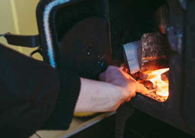 Kindling starting to burn with bright orange flame as the stove is lit with a match in Barrow shepherd's hut