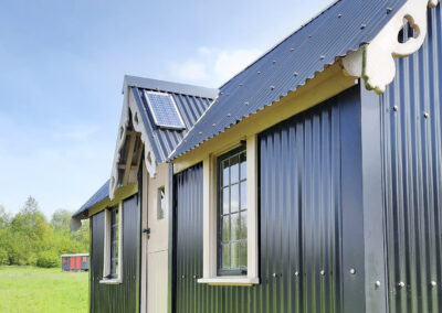 Side view of The Wriggly Inn with gables and leaded windows, showing the solar panel on the gable for charging phones from USB sockets inside this ensuite shepherds hut