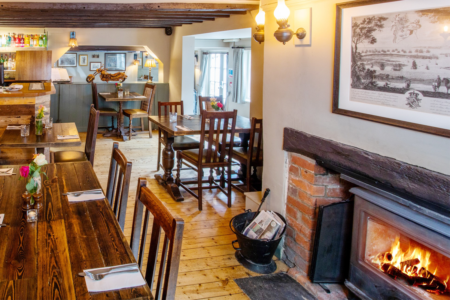Beamed interior with roaring fire and wooden dining furniture and oak flooring in a local country pub for eating out nearby